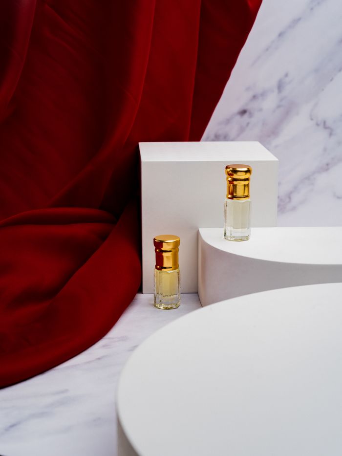 Offerings Sophisticated perfume bottles displayed on a marble surface with a striking red backdrop, exuding elegance.